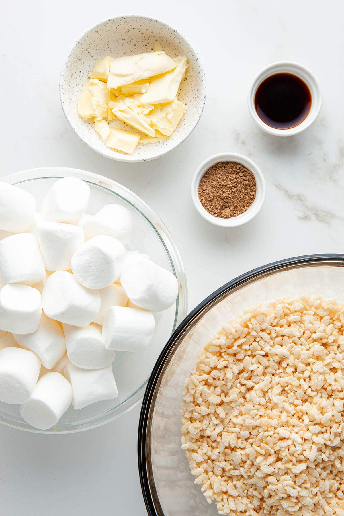 Ingredients to make chai-spiced Rice Krispie treats laid out on a white stone surface.