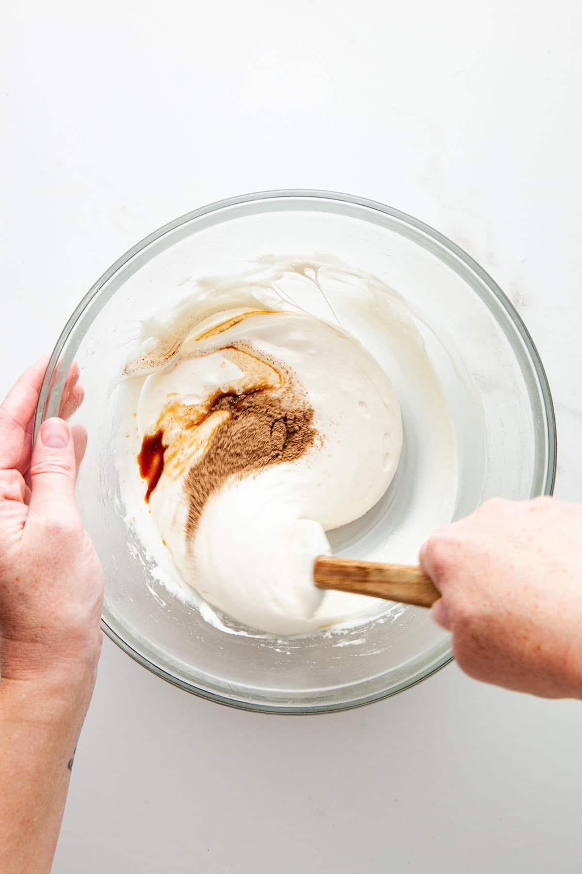 A hand mixing melted marshmallow, spices, and vanilla.