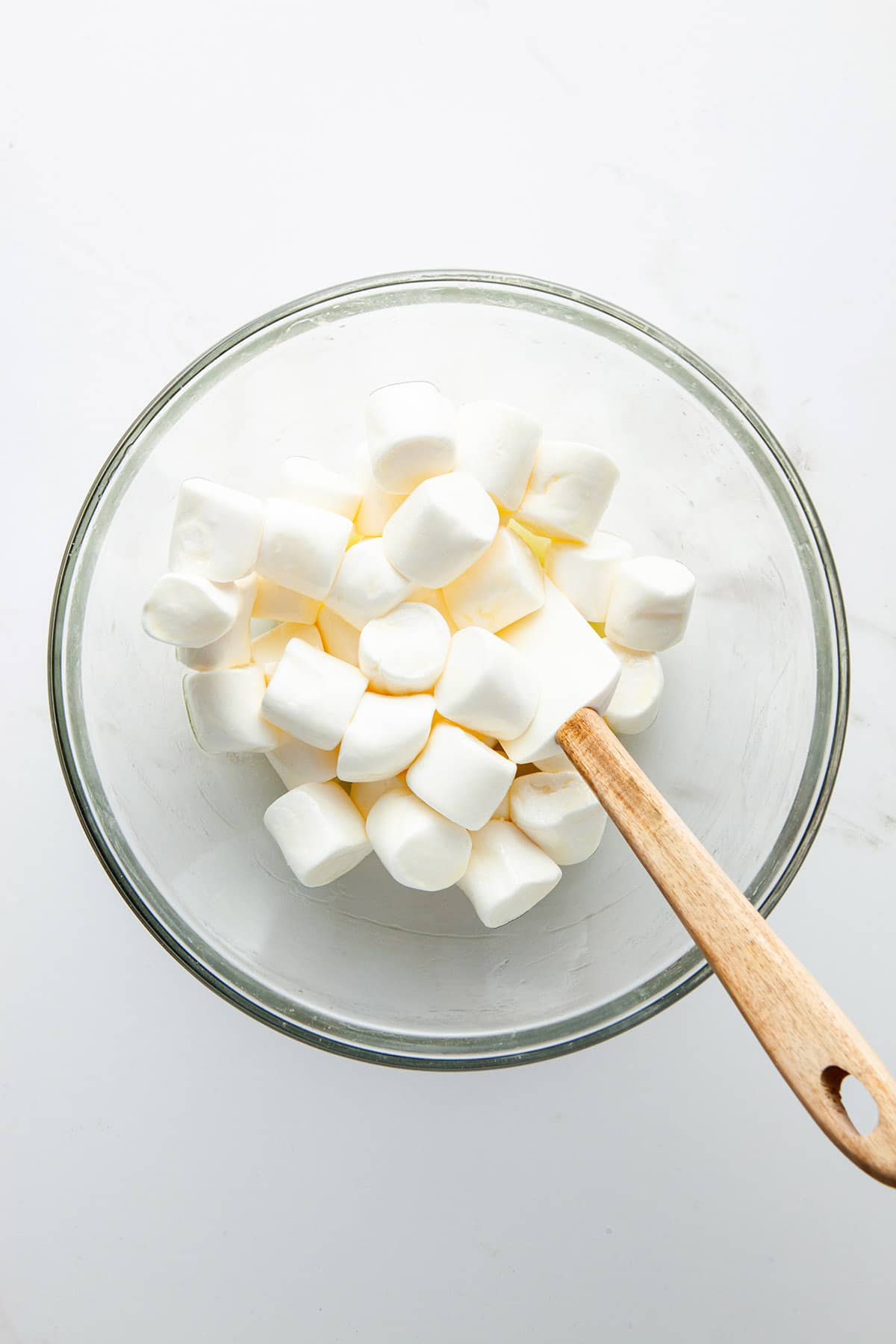 A glass bowl of marshmallows that have been stirred with melted butter.