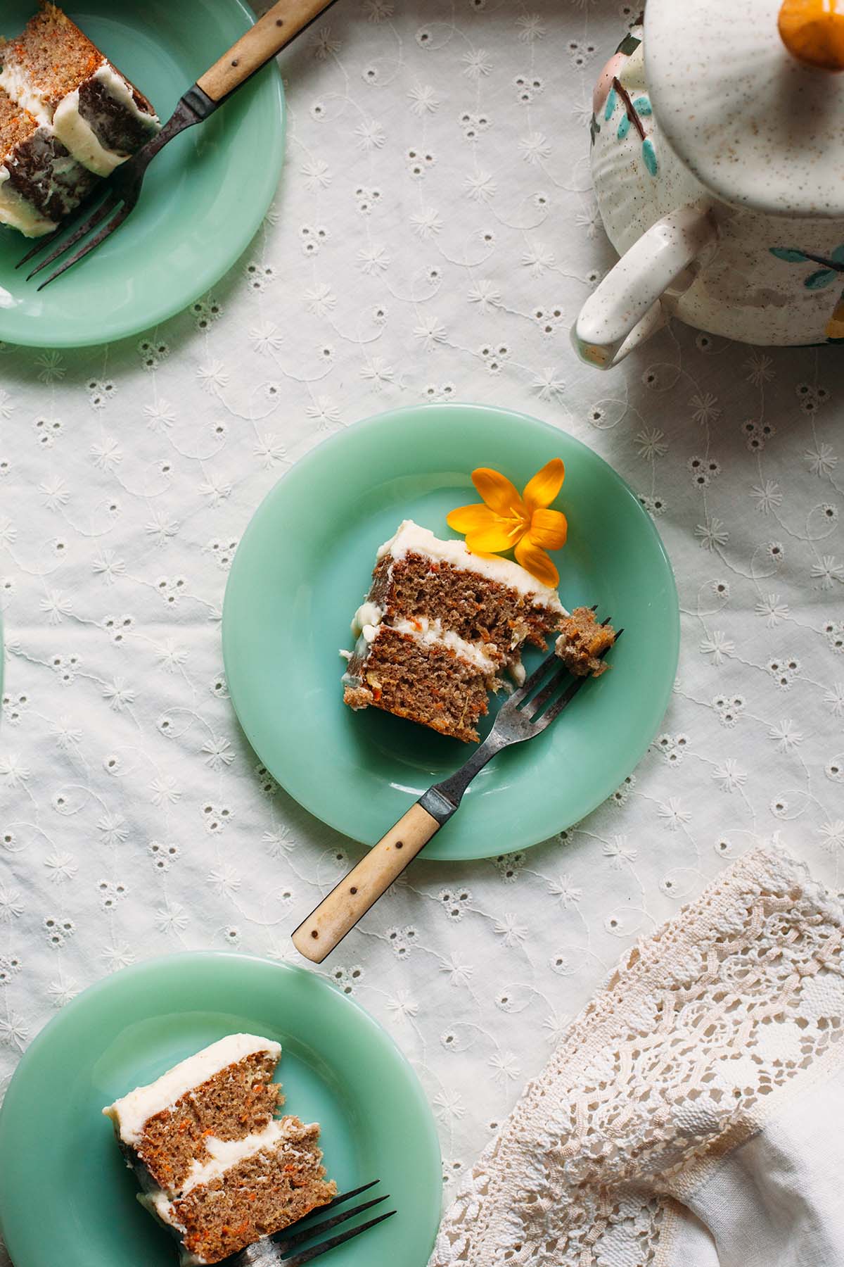 Overhead shot of a slice of spiced carrot cake on a green milk glass plate.