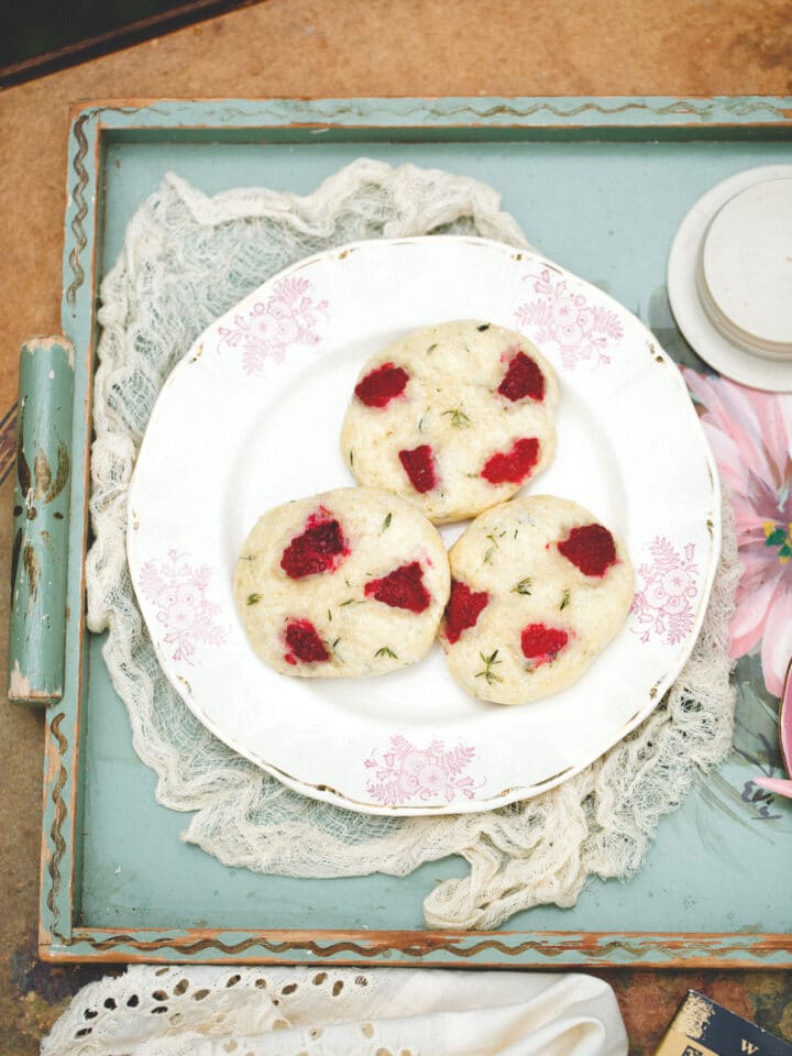 Raspberry thyme scones on a pink and white plate on a green floral serving tray.