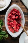 A dish of chunks of watermelon tossed with lime juice, mint, and ginger.