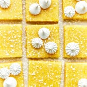 Sliced lemon bars topped with a sprinkle of powdered sugar and two styles of mini meringues.
