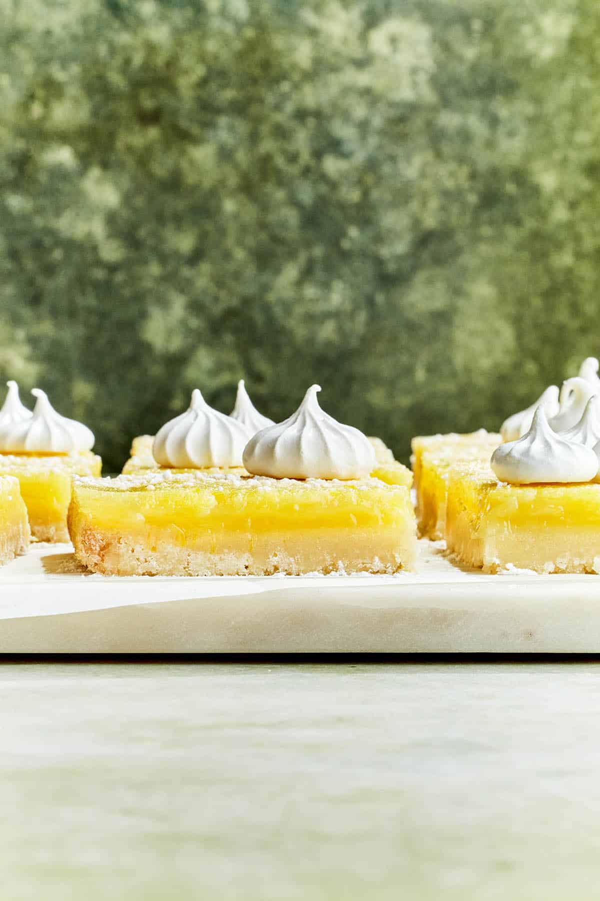Lemon squares on a marble board topped with mini meringues.