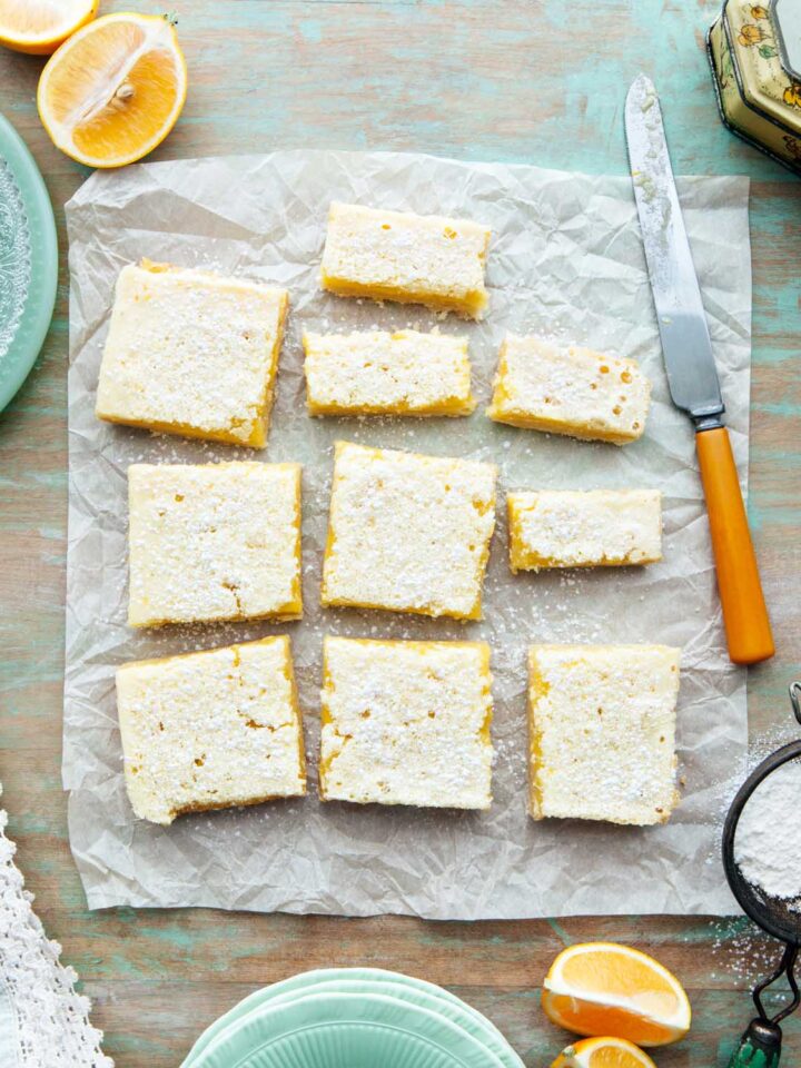 Overhead shot of classic lemon bars with shortbread crust on a green table.