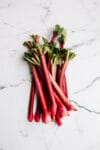 A bundle of rhubarb stalks on a marble background.