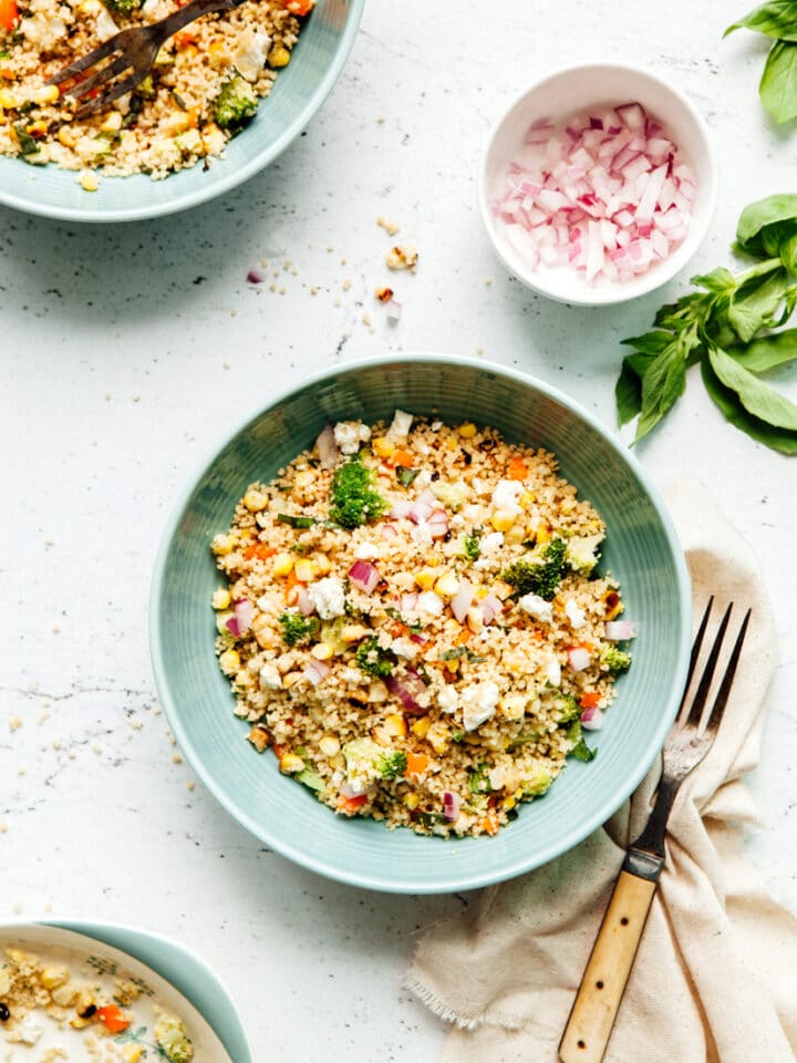 A bowl of charred corn couscous salad with feta and basil.