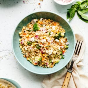 A bowl of couscous salad with feta and basil.