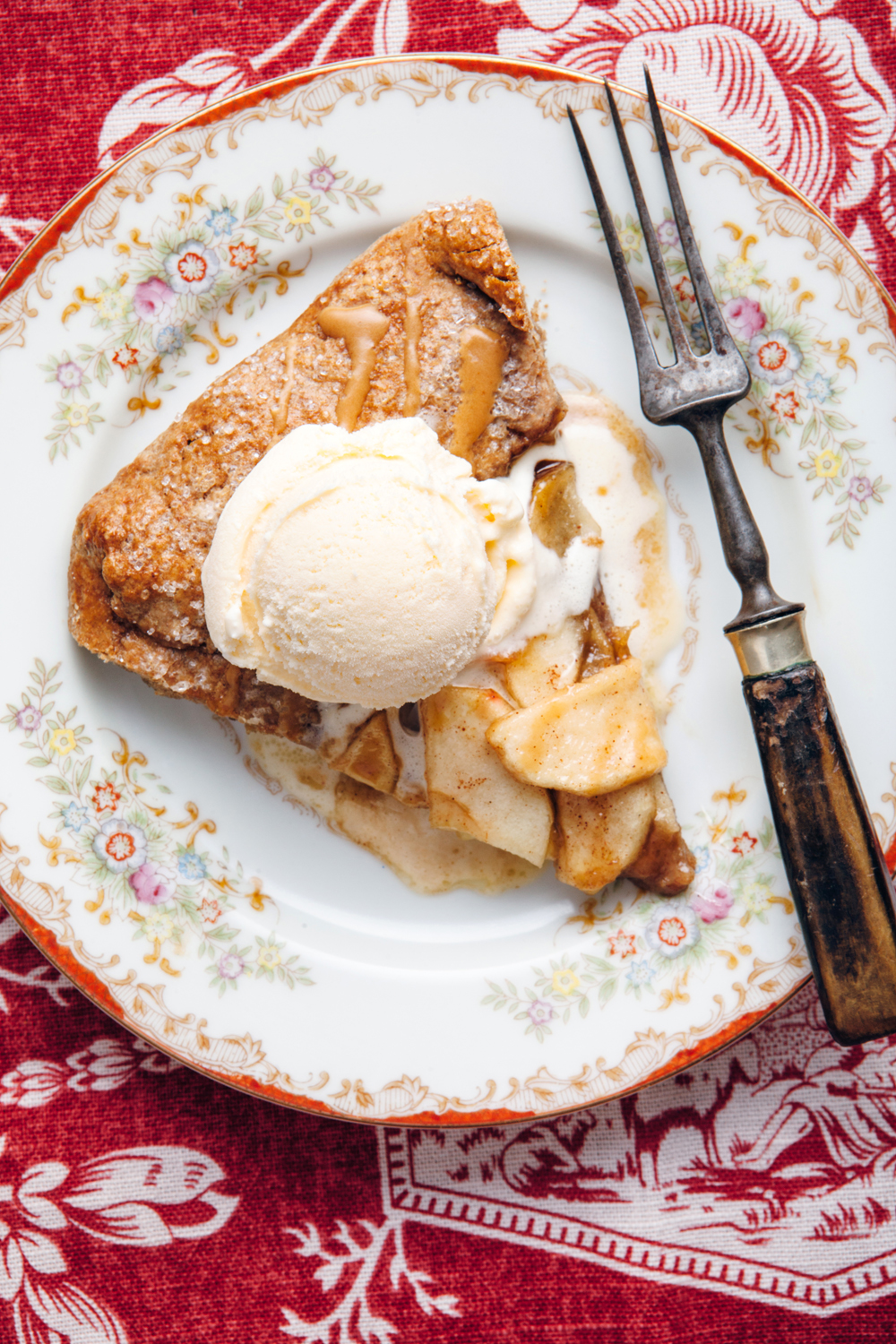 A slice of spicy apple galette with coffee glaze topped with ice cream.