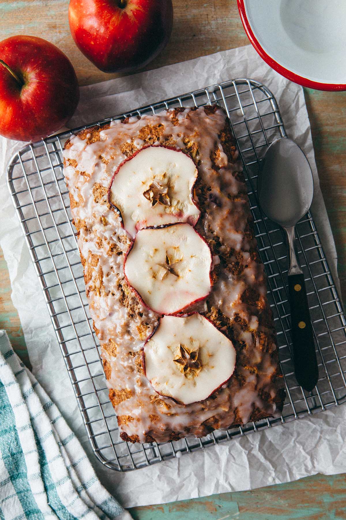 An apple loaf cake on a wire rack topped with apple cider glaze.