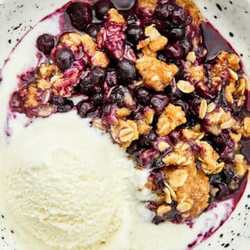 Wild blueberry crisp in a bowl with ice cream.