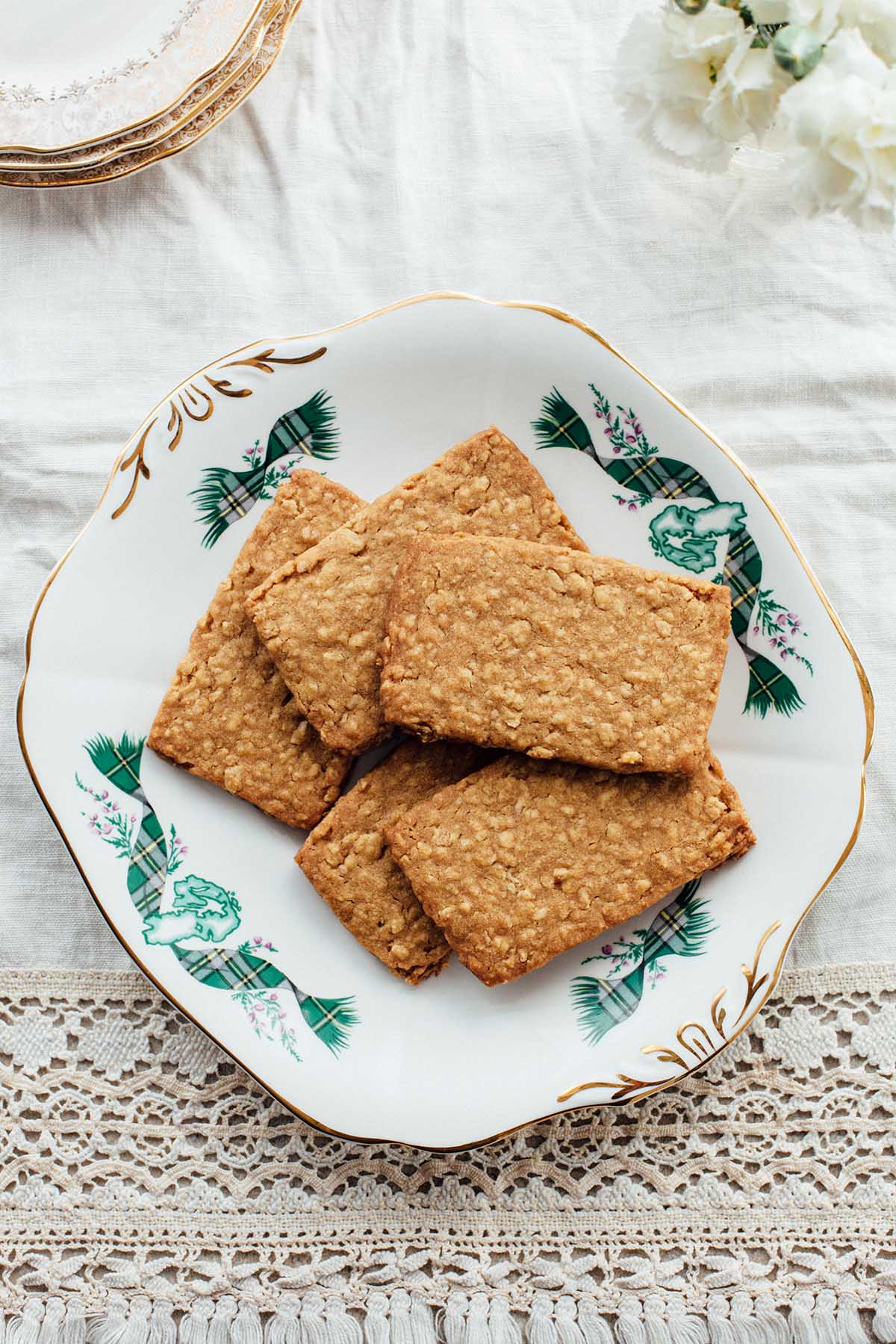 A platter of Nova Scotia oatcakes on a table with plates and a vase of white flowers.
