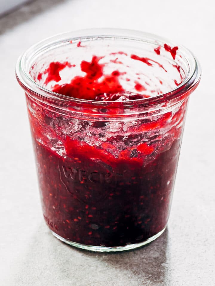 A jar of raspberry rhubarb jam on a table.