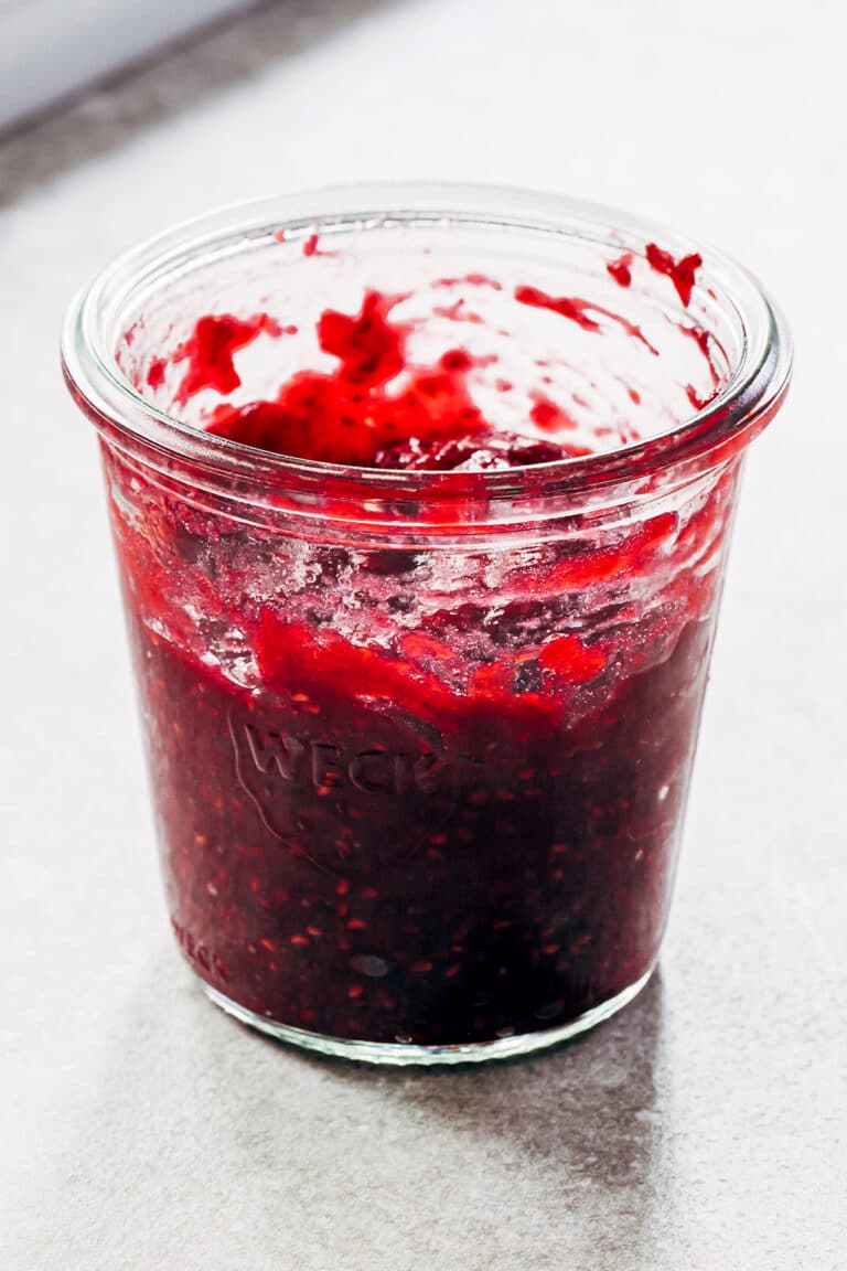 A jar of raspberry rhubarb jam on a table.
