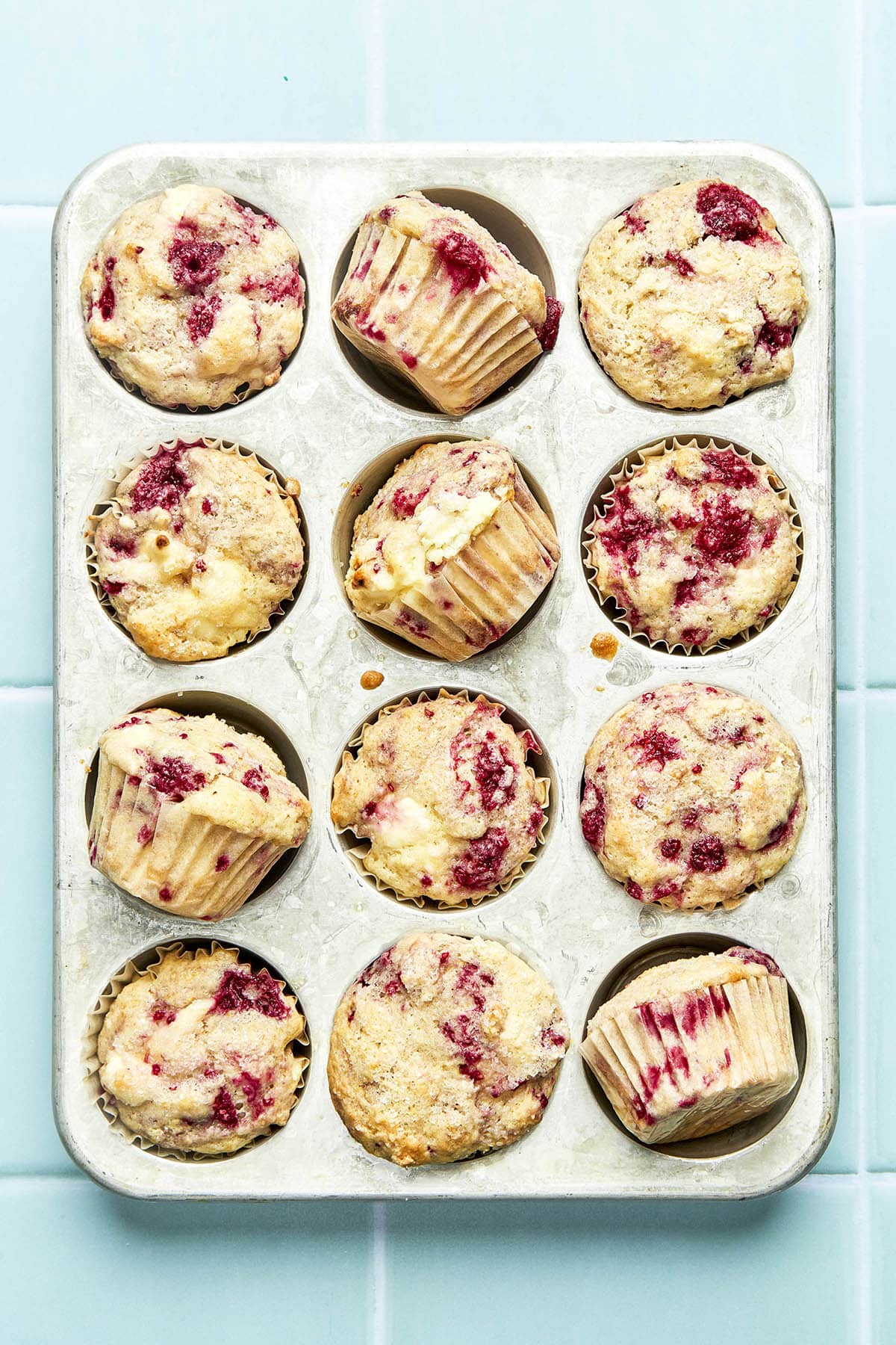 Baked muffins in a muffin tin with four of the muffins turned sideways to show the sides of each muffin.