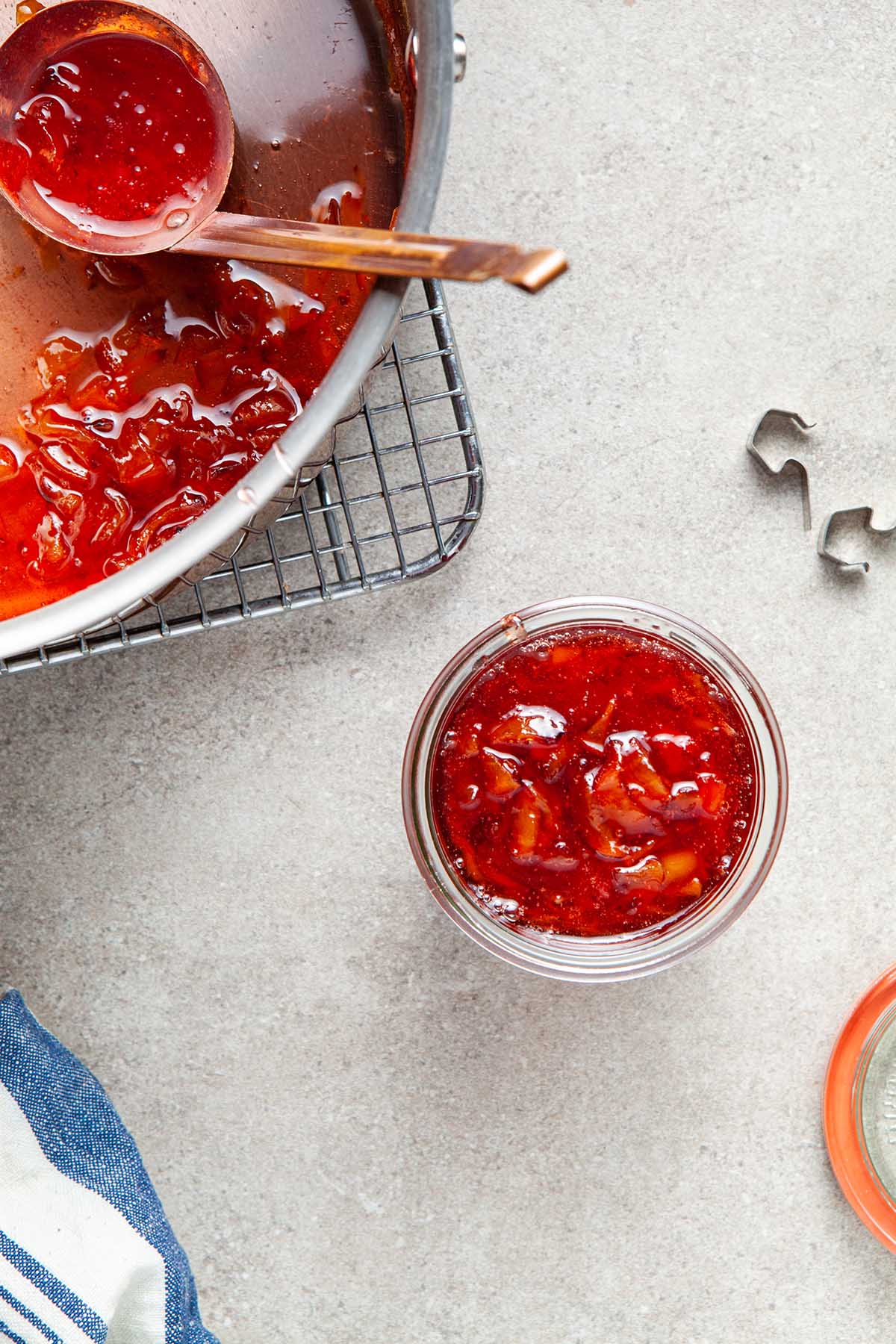 A jar of maple peach whisky jam next to a pot of jam.