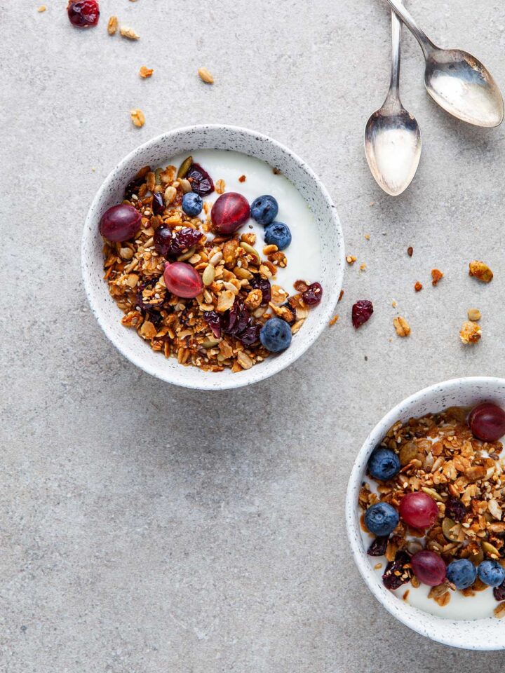 Bowls of yogurt topped with nut-free granola, gooseberries, and blueberries.