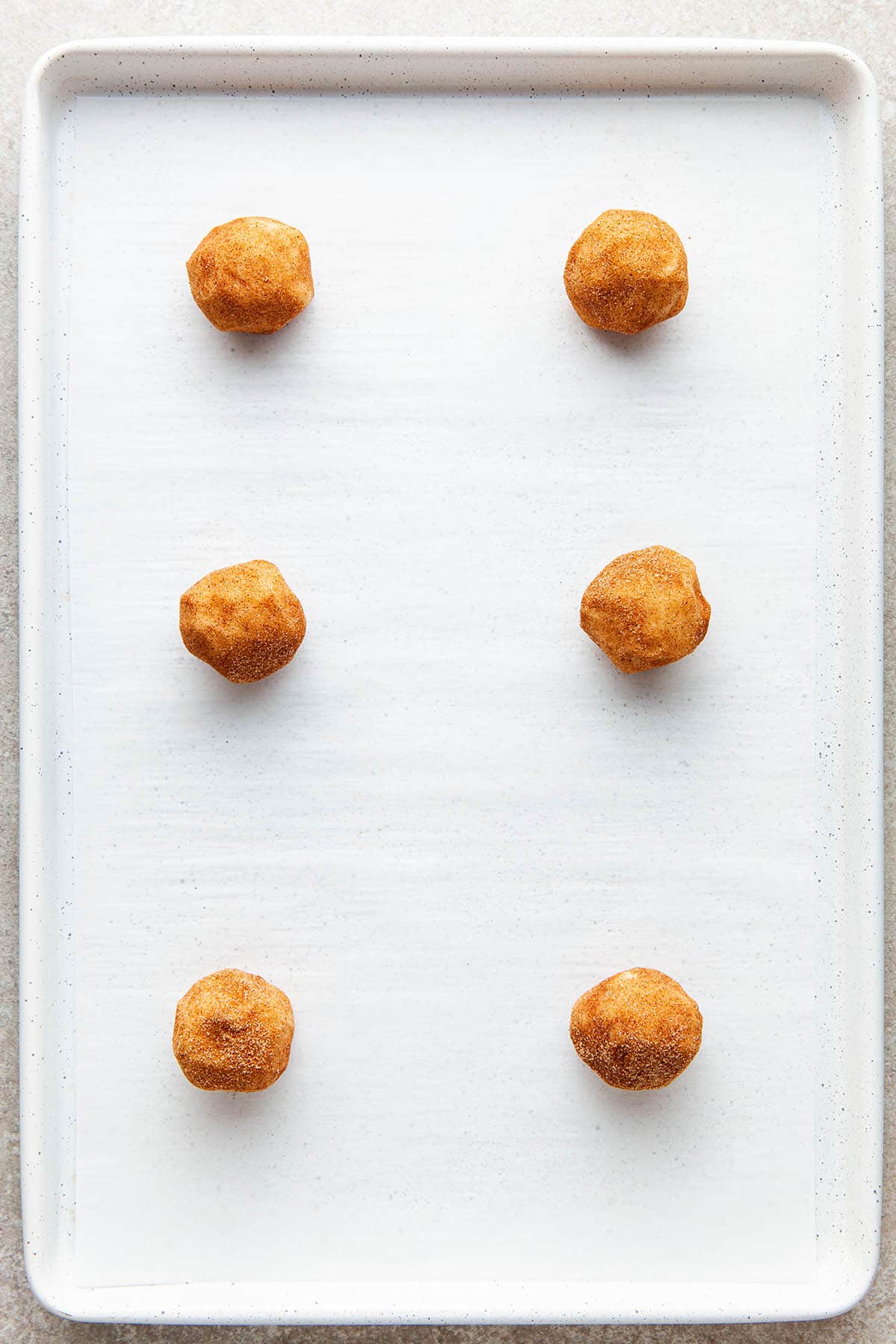 Six unbaked cookie balls on a baking sheet.