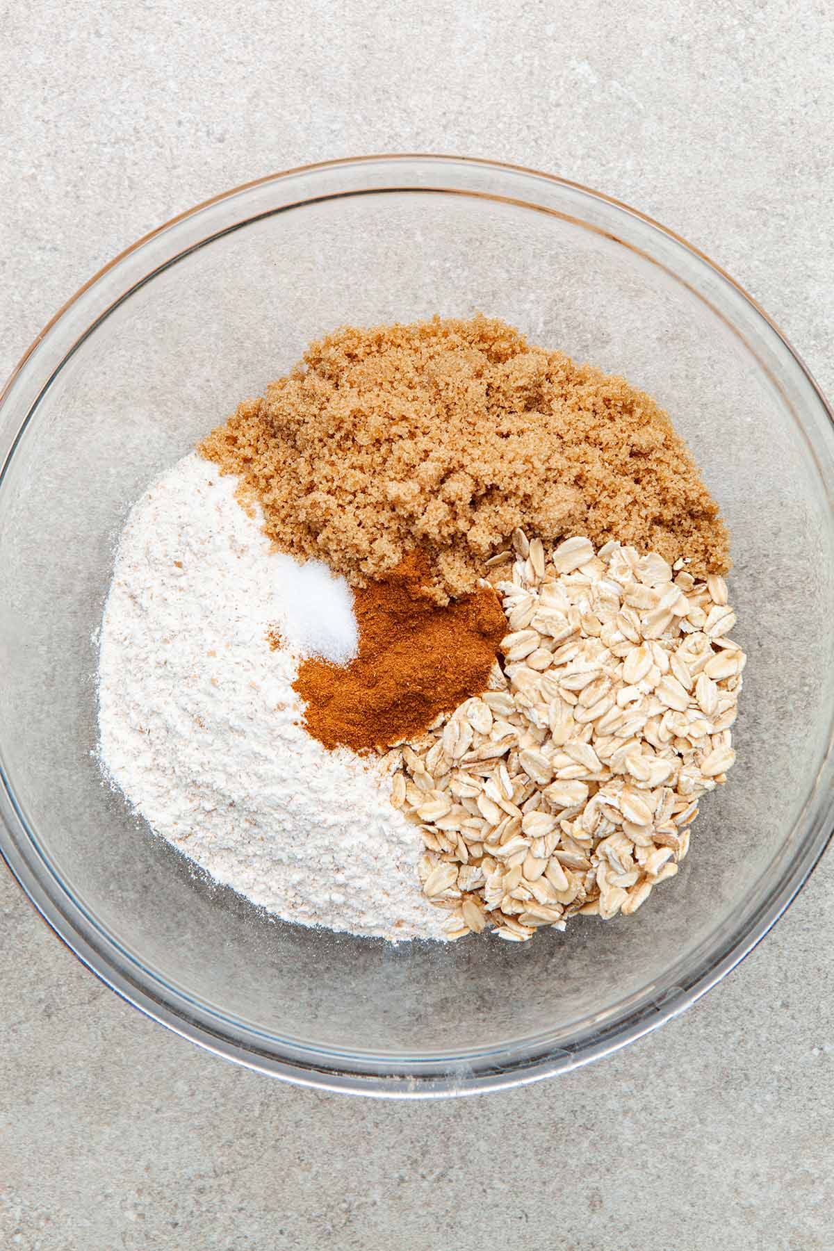 A bowl of oats, flour, brown sugar, cinnamon, and salt unmixed.