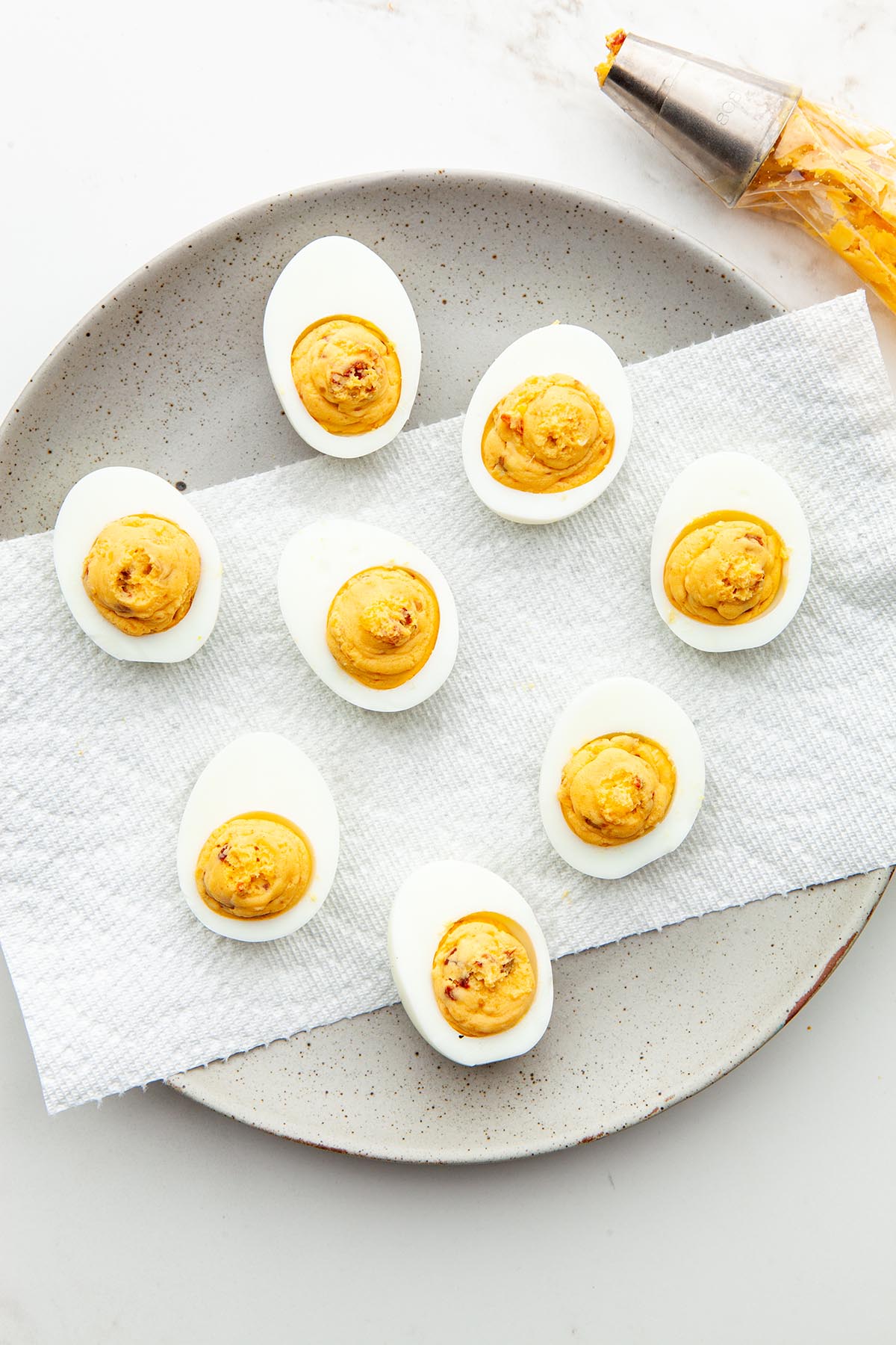A grey plate of hard boiled egg whites with mash yolk filling piped in the middle of each.
