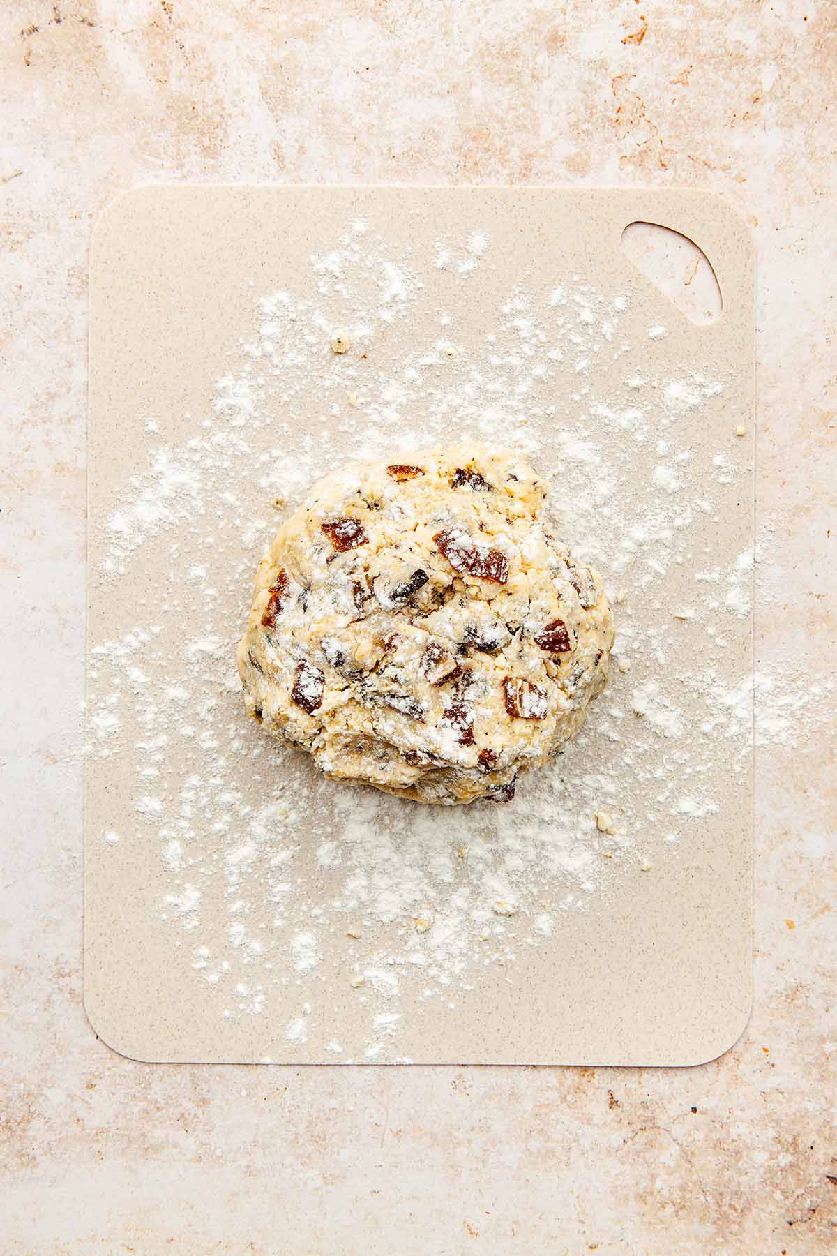 A ball of dough sprinkled with flour on a lightly floured work surface.