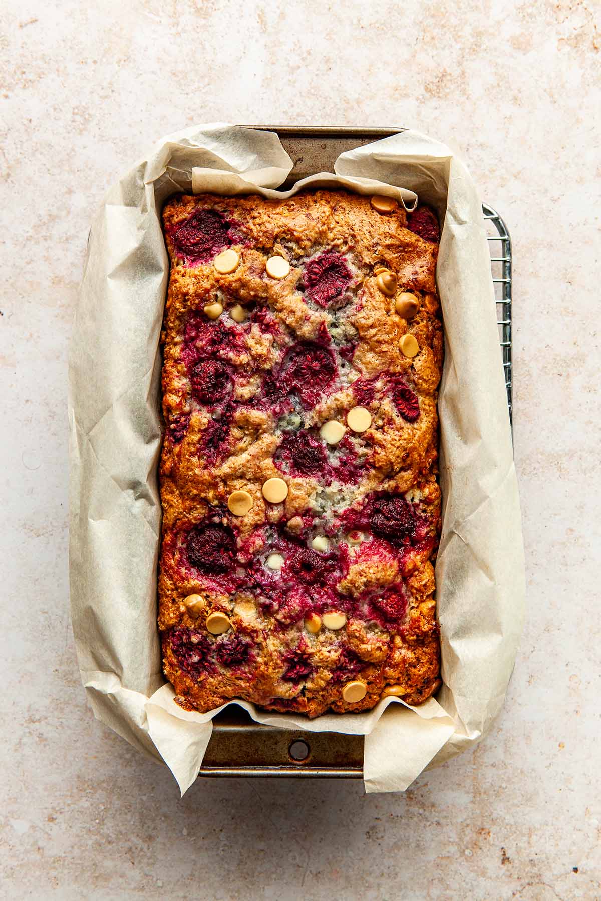 A fully baked raspberry and white chocolate loaf cake still in the loaf tin.