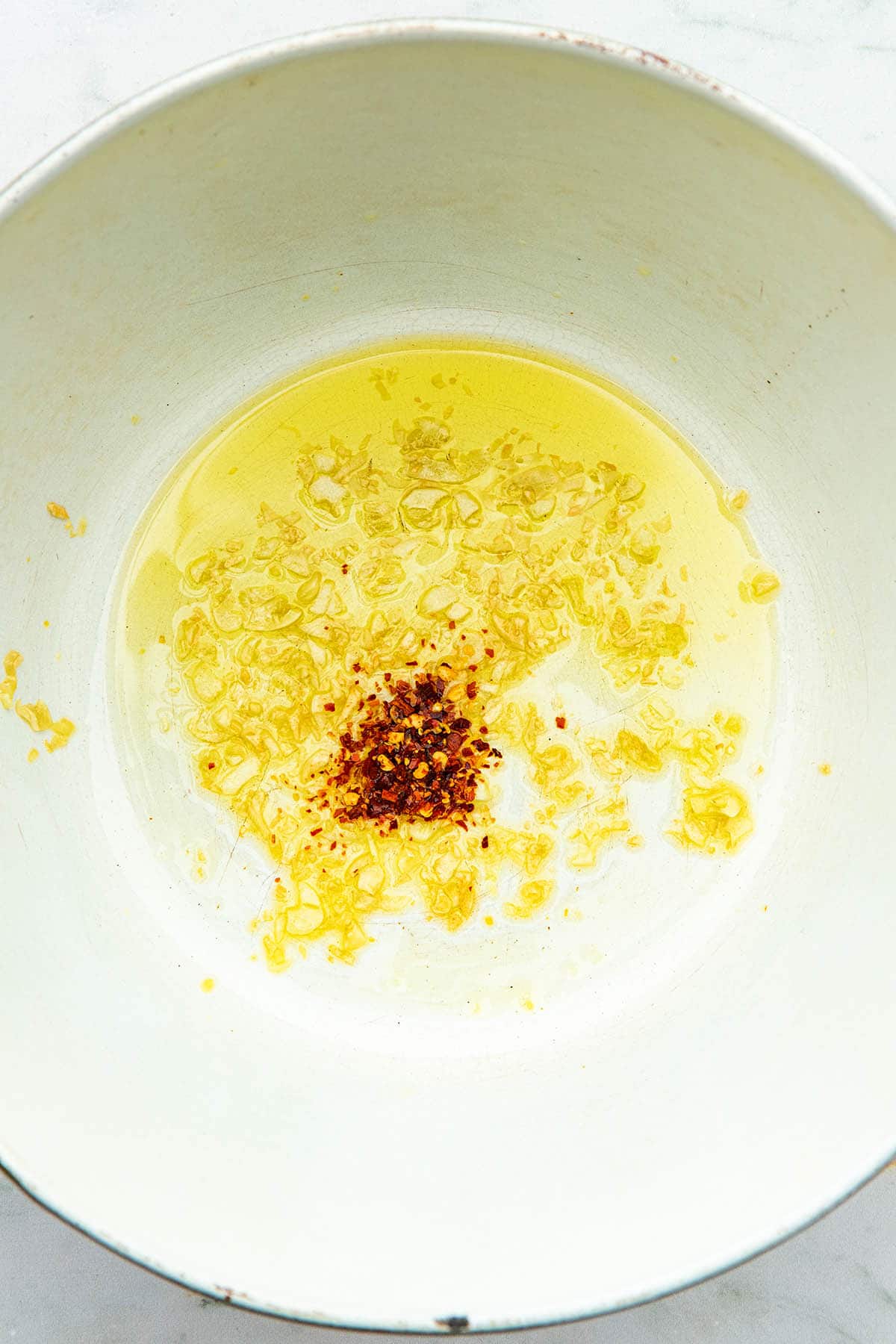 Chopped garlic, chilli flakes, and olive oil in the bottom of a pot.