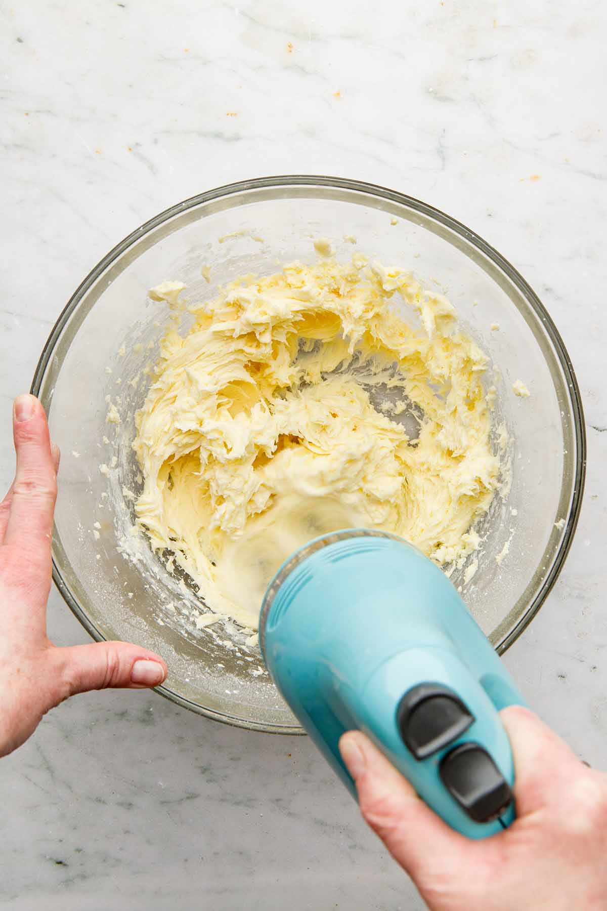 A hand using a hand mixer to mix a batch of Nanny Burke's buttercream.