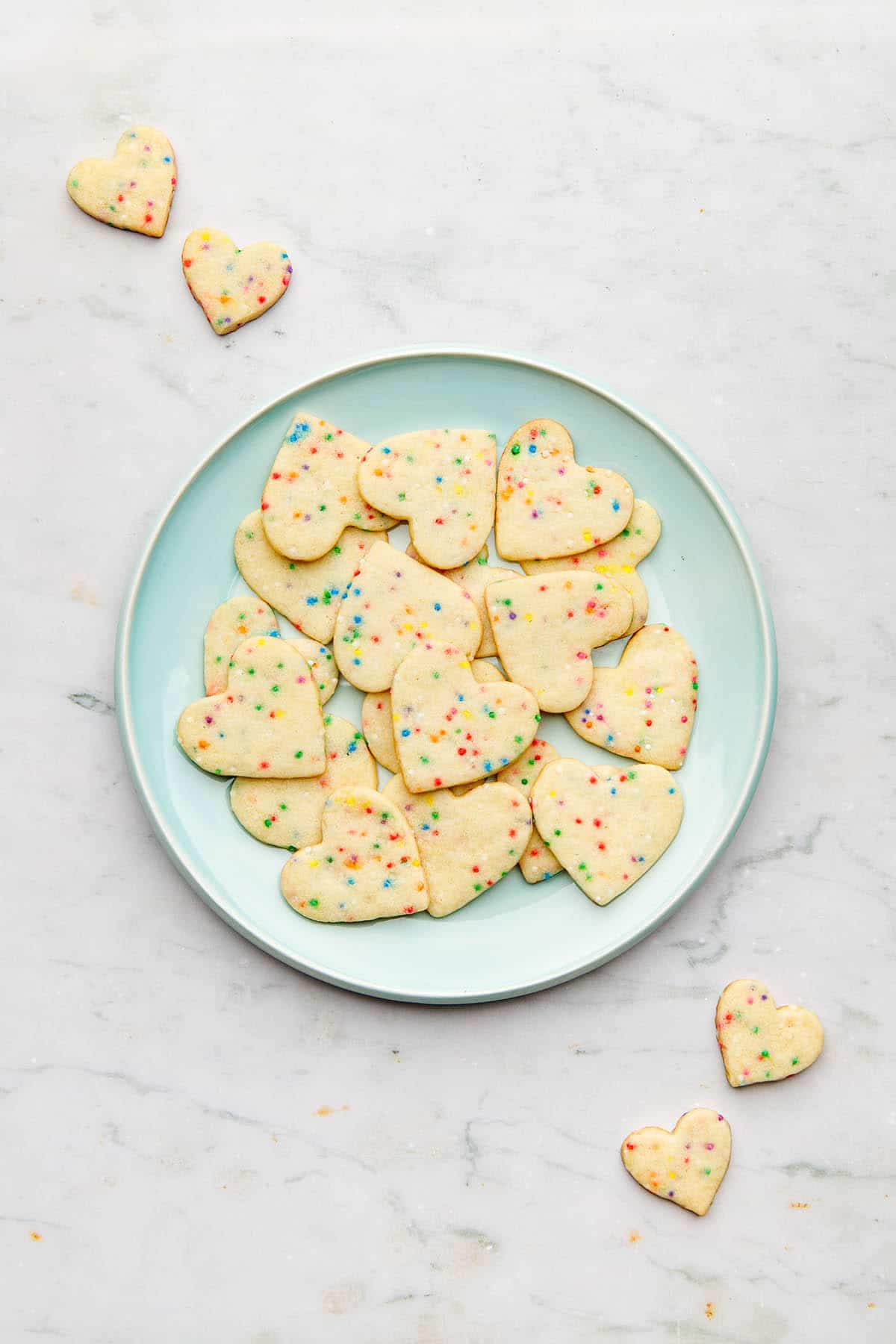 An aqua-coloured ceramic plate with sugar cookies with sprinkles.