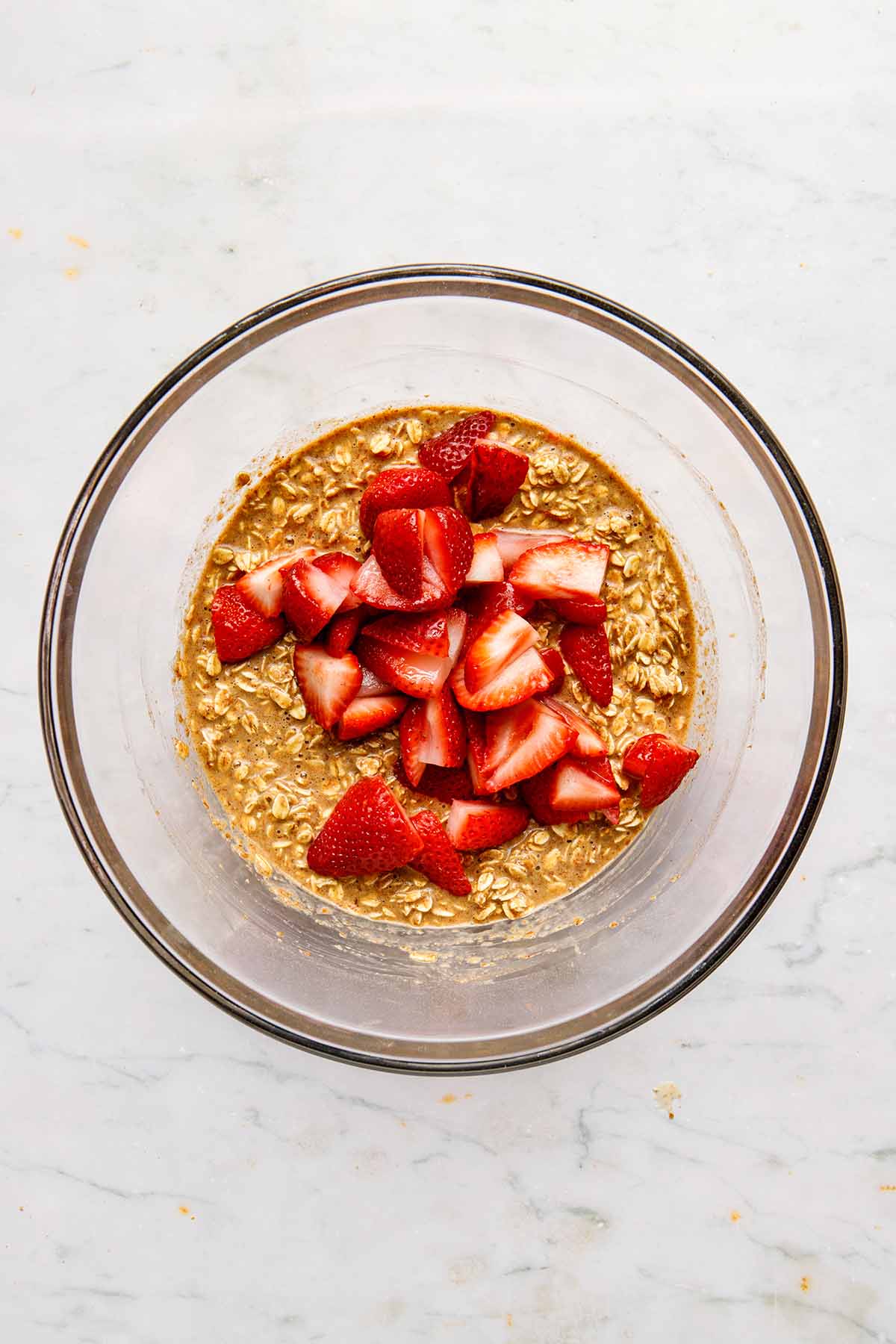 Wet oatmeal in a bowl topped with sliced strawberries.
