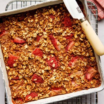 Overhead image of strawberry baked oatmeal in a squre tin with a knife on the edge of the tin.
