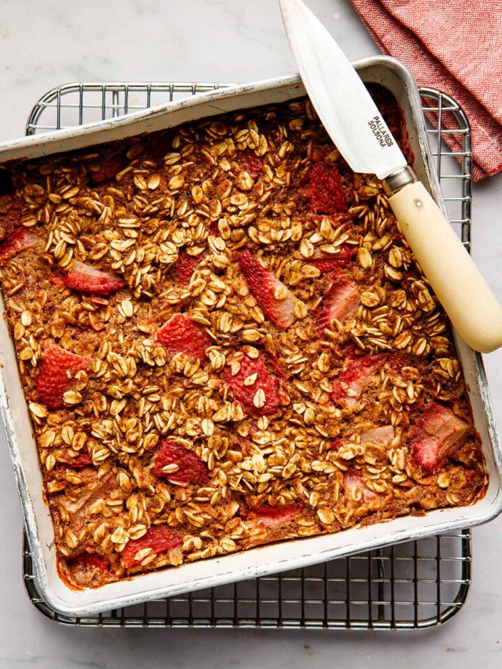Overhead image of strawberry baked oatmeal in a squre tin with a knife on the edge of the tin.