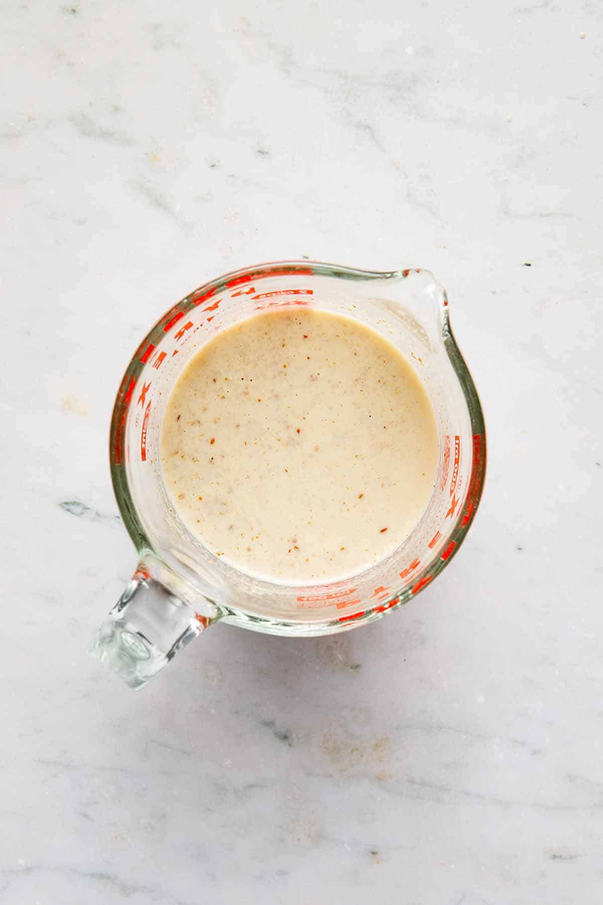 Plant-based milk, flax meal, and vanilla mixed together in a measuring cup.