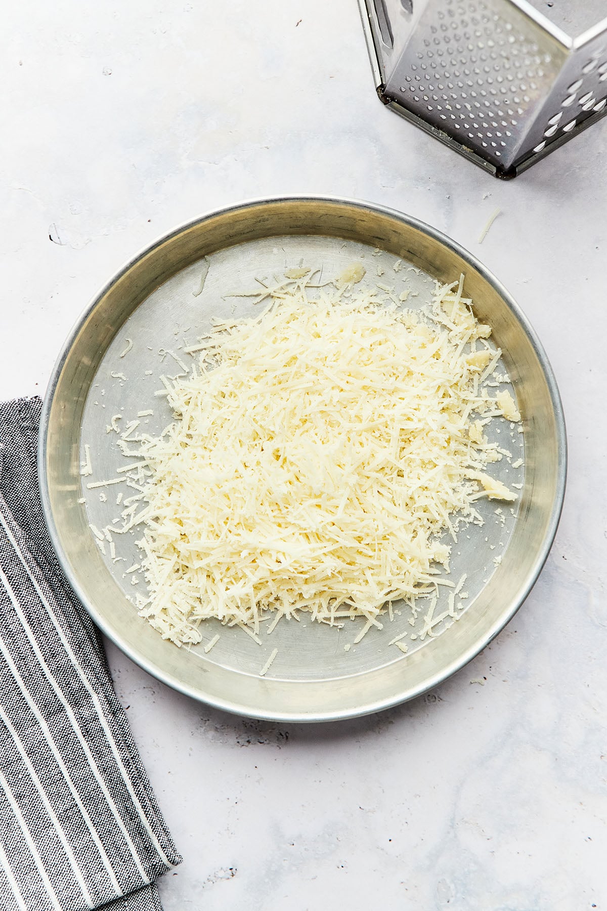 A small round metal tray with grated Parmesan cheese inside.