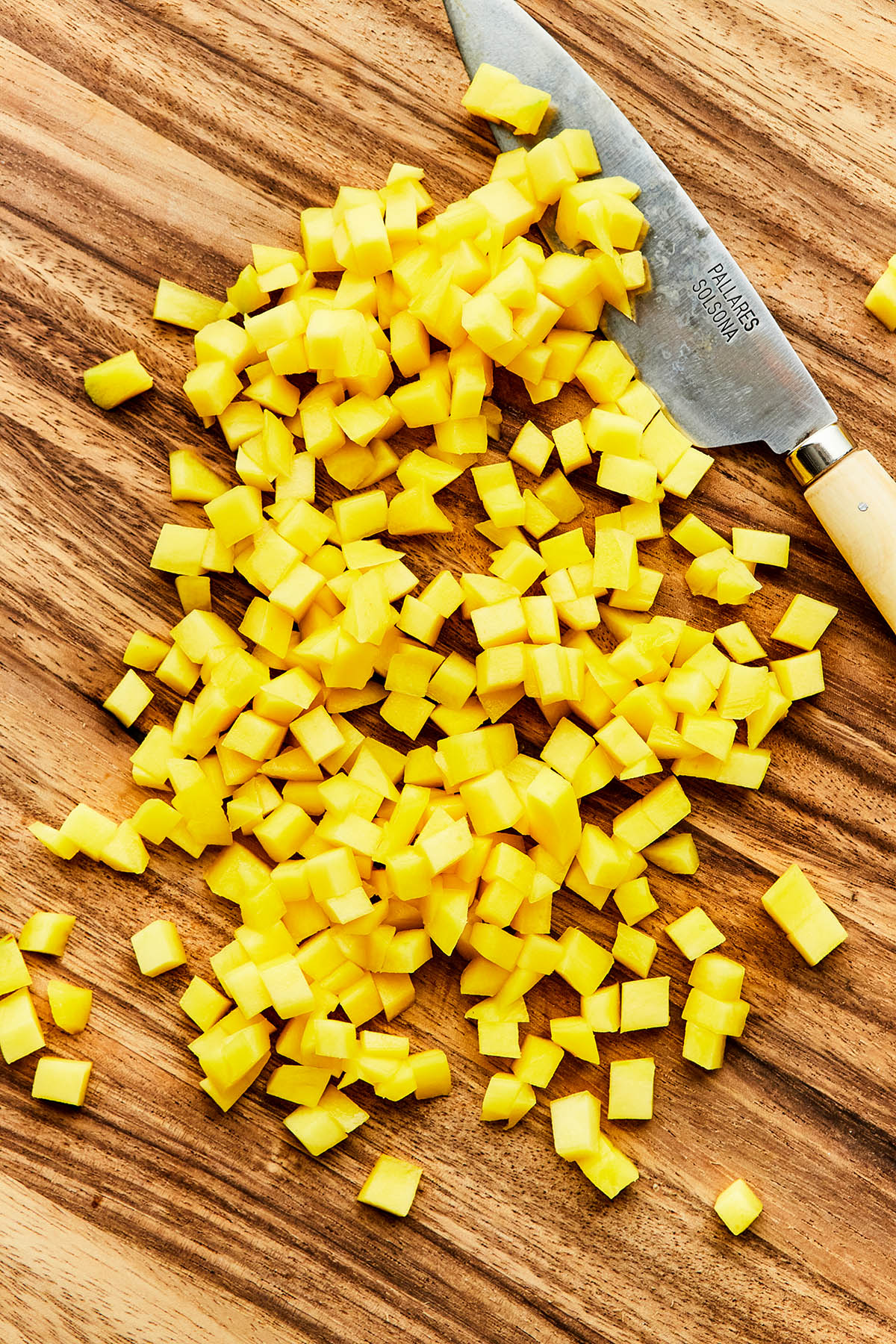 Finely diced mango on a wooden cutting board.