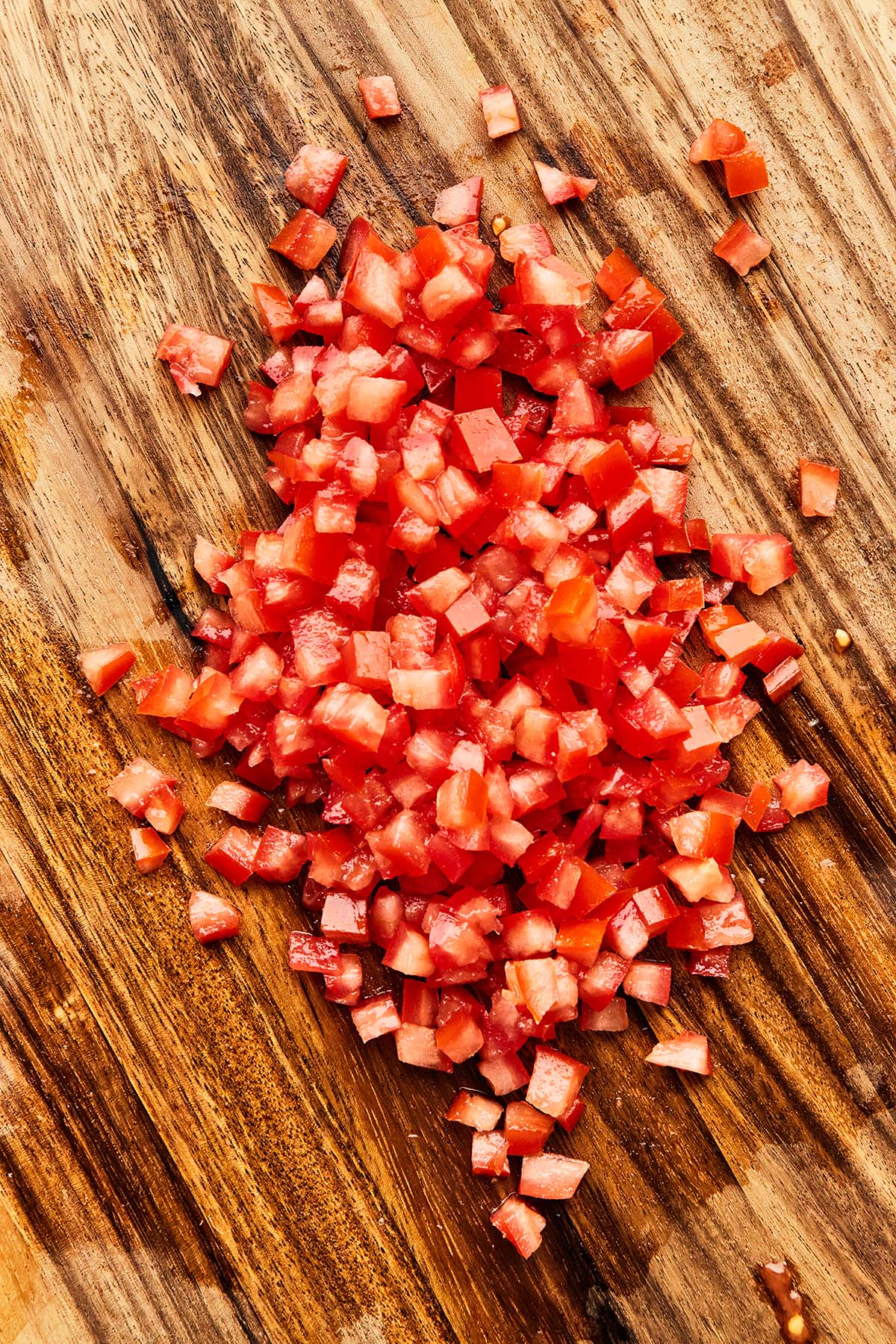 Finely diced tomatoes on a wooden cutting board.
