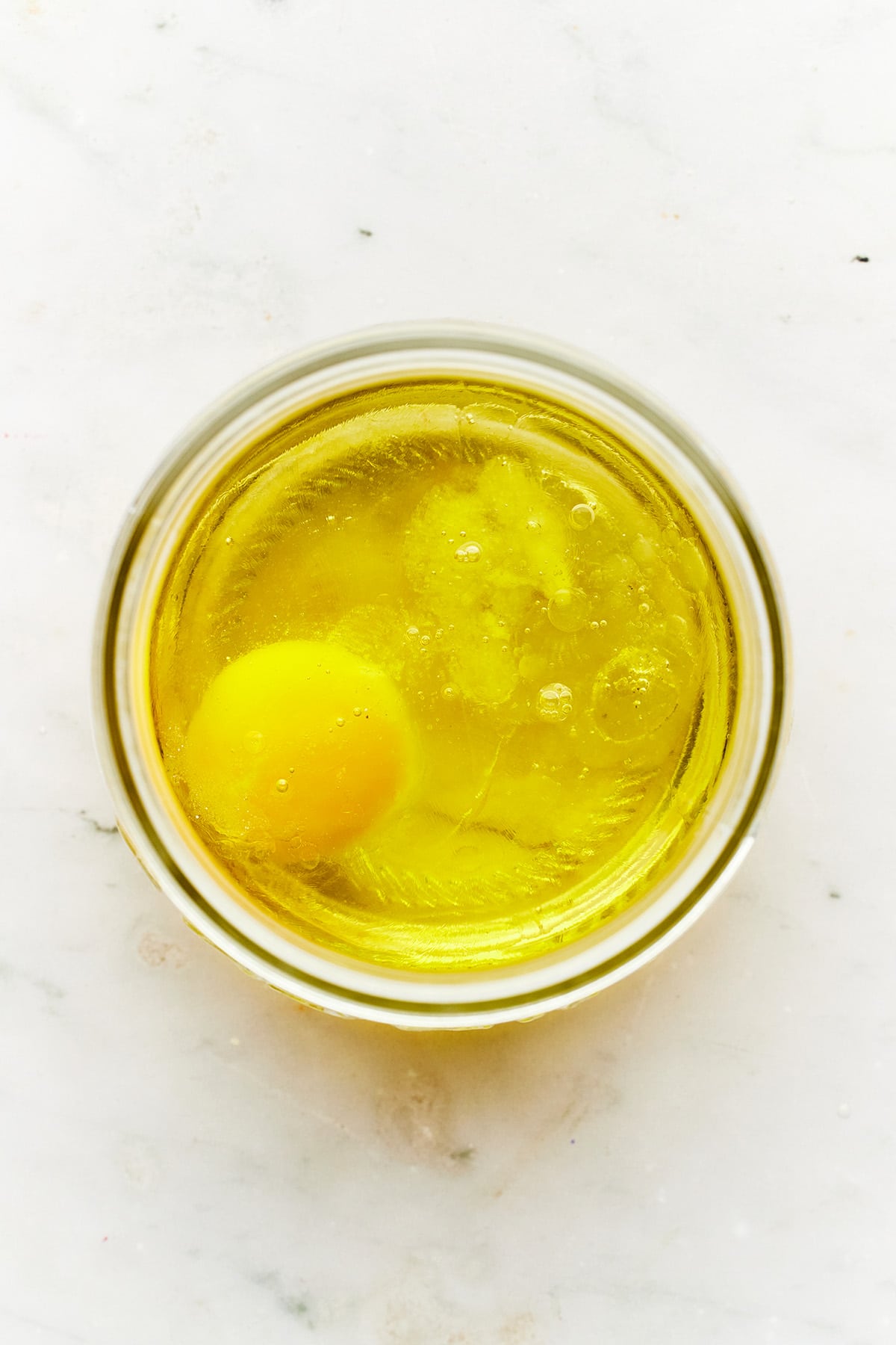 A jar with oil, salt, and an egg inside.