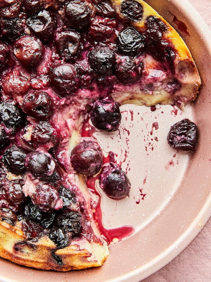 Close up of a pan of cherry clafoutis with a serving missing.