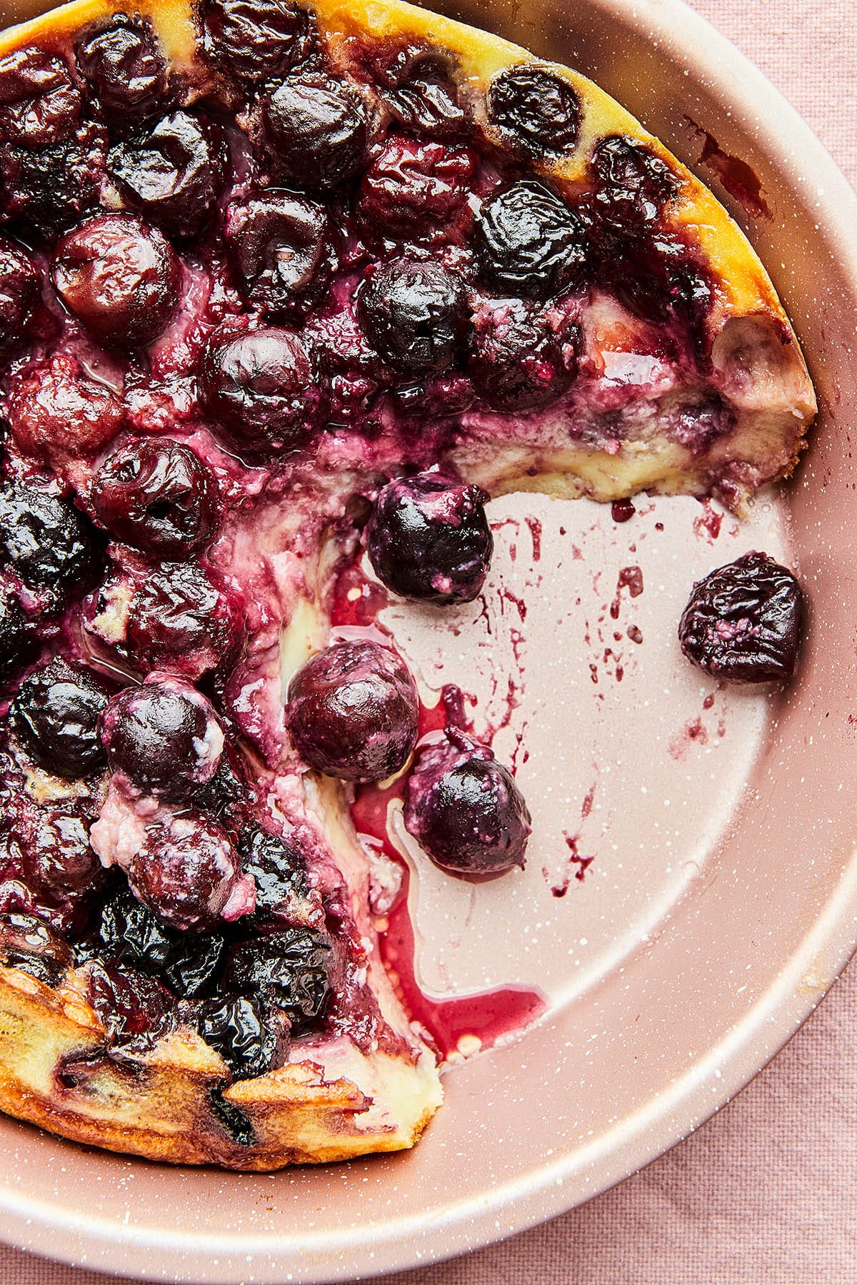Close up of a pan of cherry clafoutis with a serving missing.