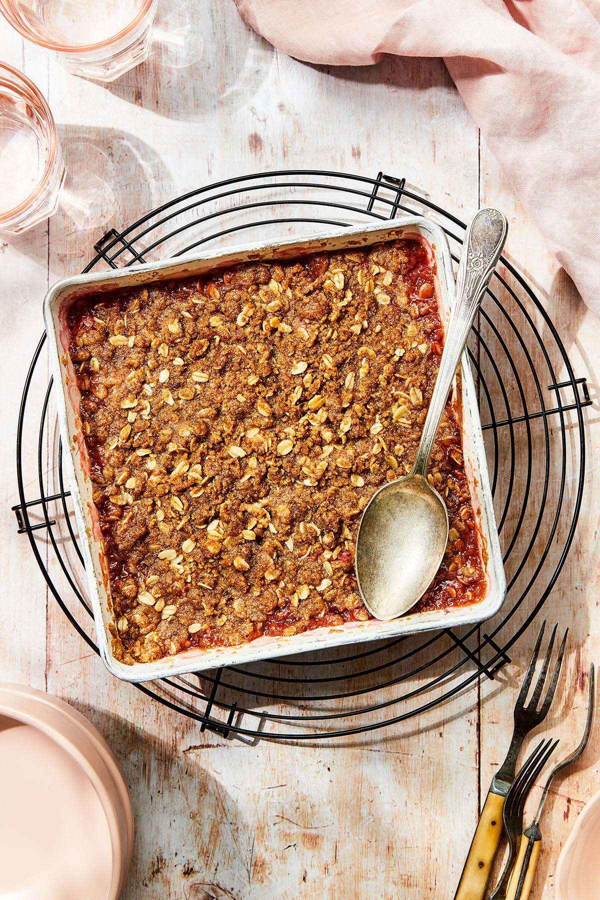 A square pan of baked gluten-free rhubarb crisp on a round wire cooling rack.