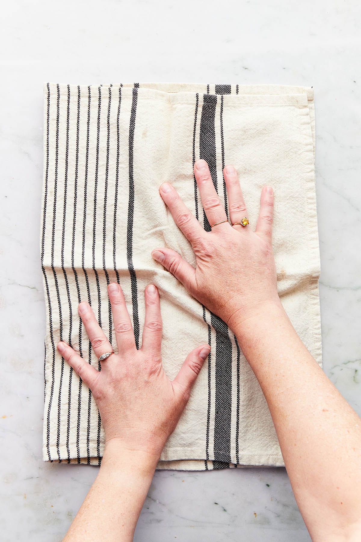 Hands rubbing chickpeas inside a folded tea towel.
