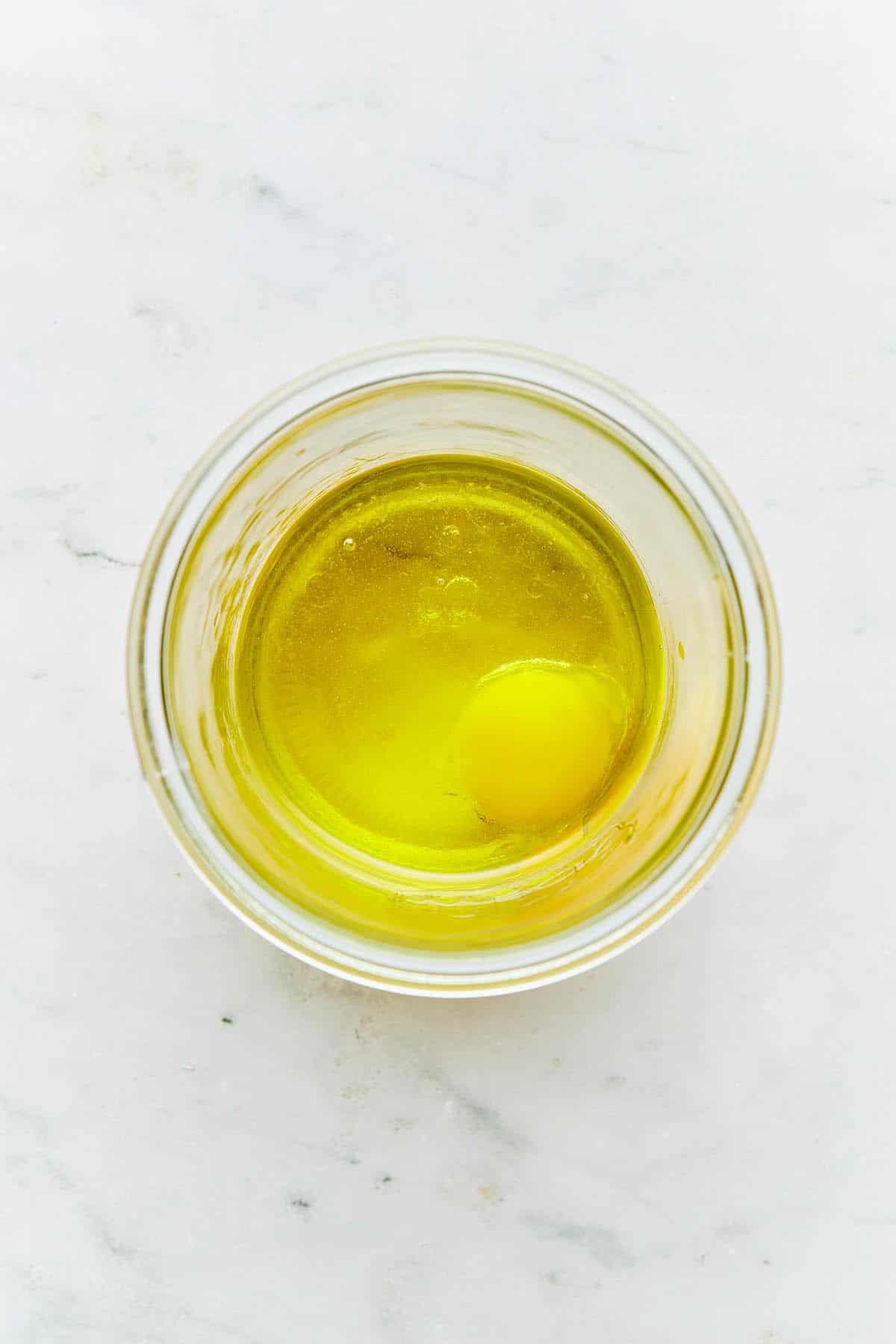 A jar of oil with an egg inside the jar.