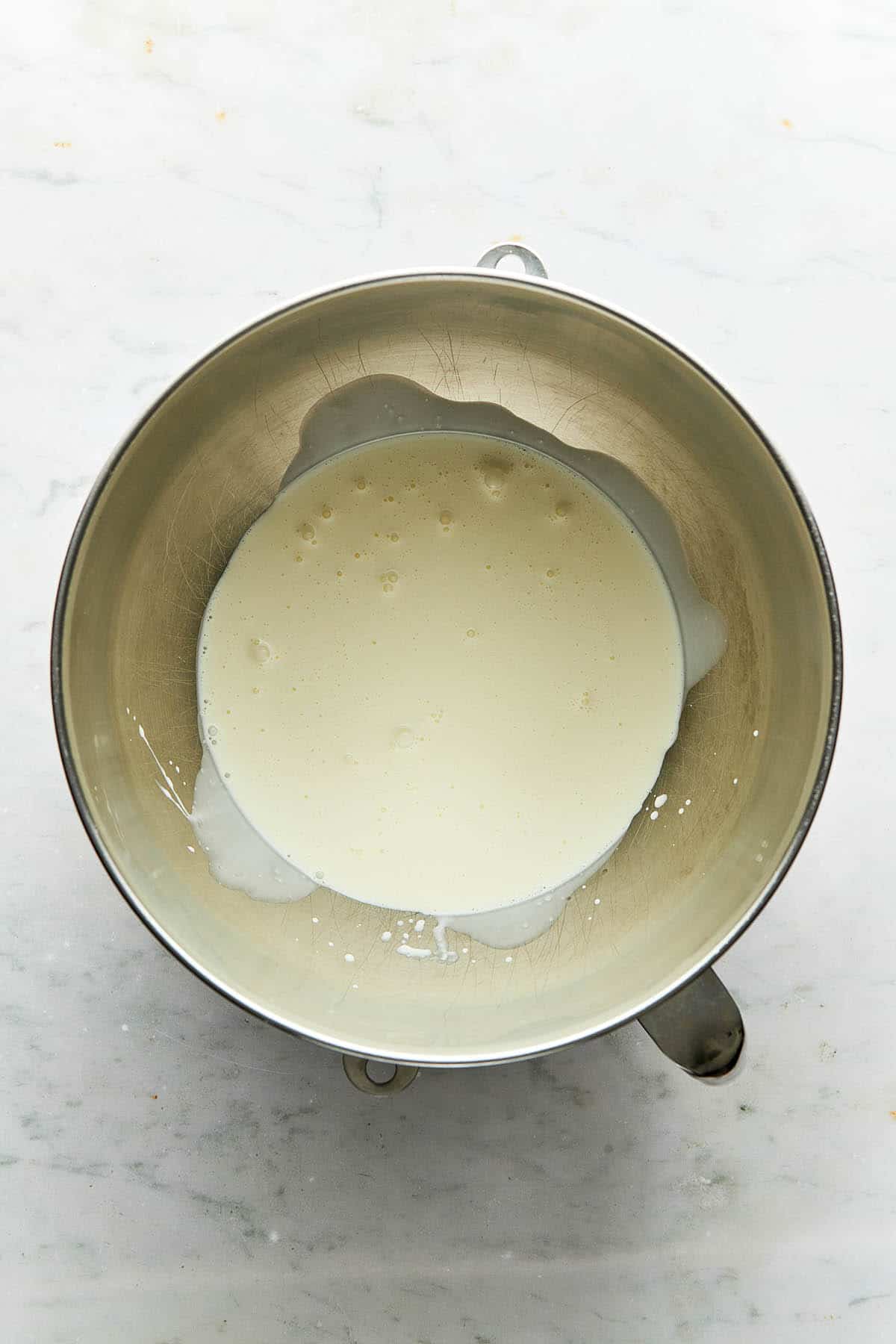Heavy cream inside a metal mixing bowl.