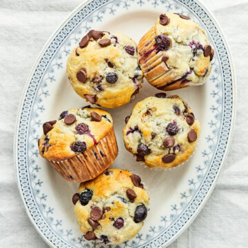 An oval platter of five blueberry chocolate chip muffins.