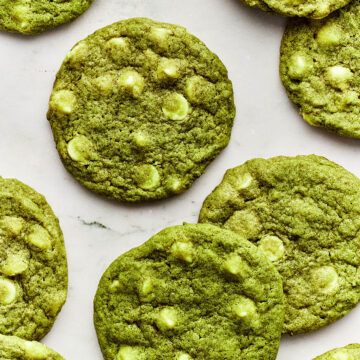 Matcha chocolate chip cookies scattered on a marble surface.