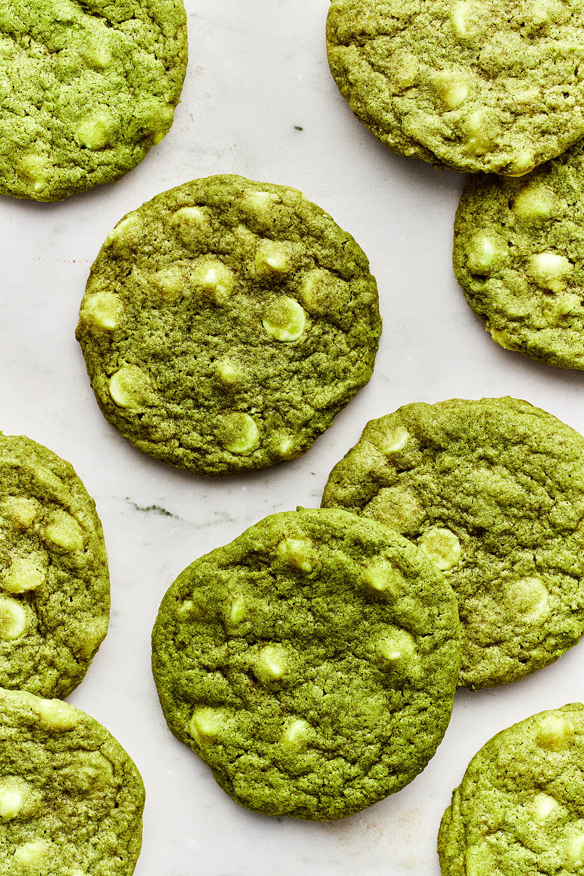 Matcha chocolate chip cookies scattered on a marble surface.
