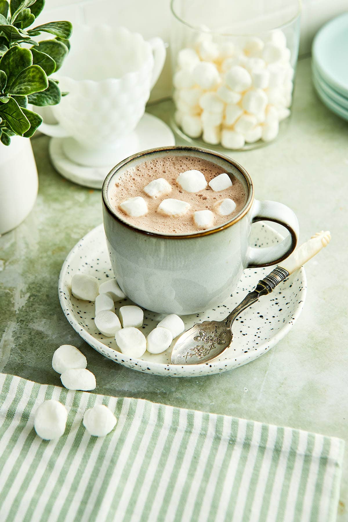 A mug of how chocolate topped with dehydrated marshmallows on a kitchen counter.