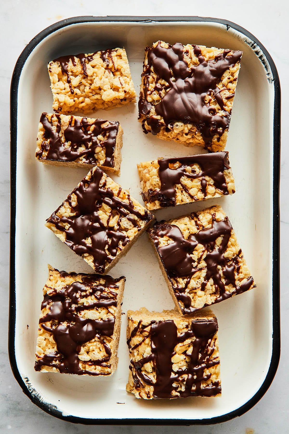 A white enamel pan with black trim filled with peanut butter Rice Krispie treats.