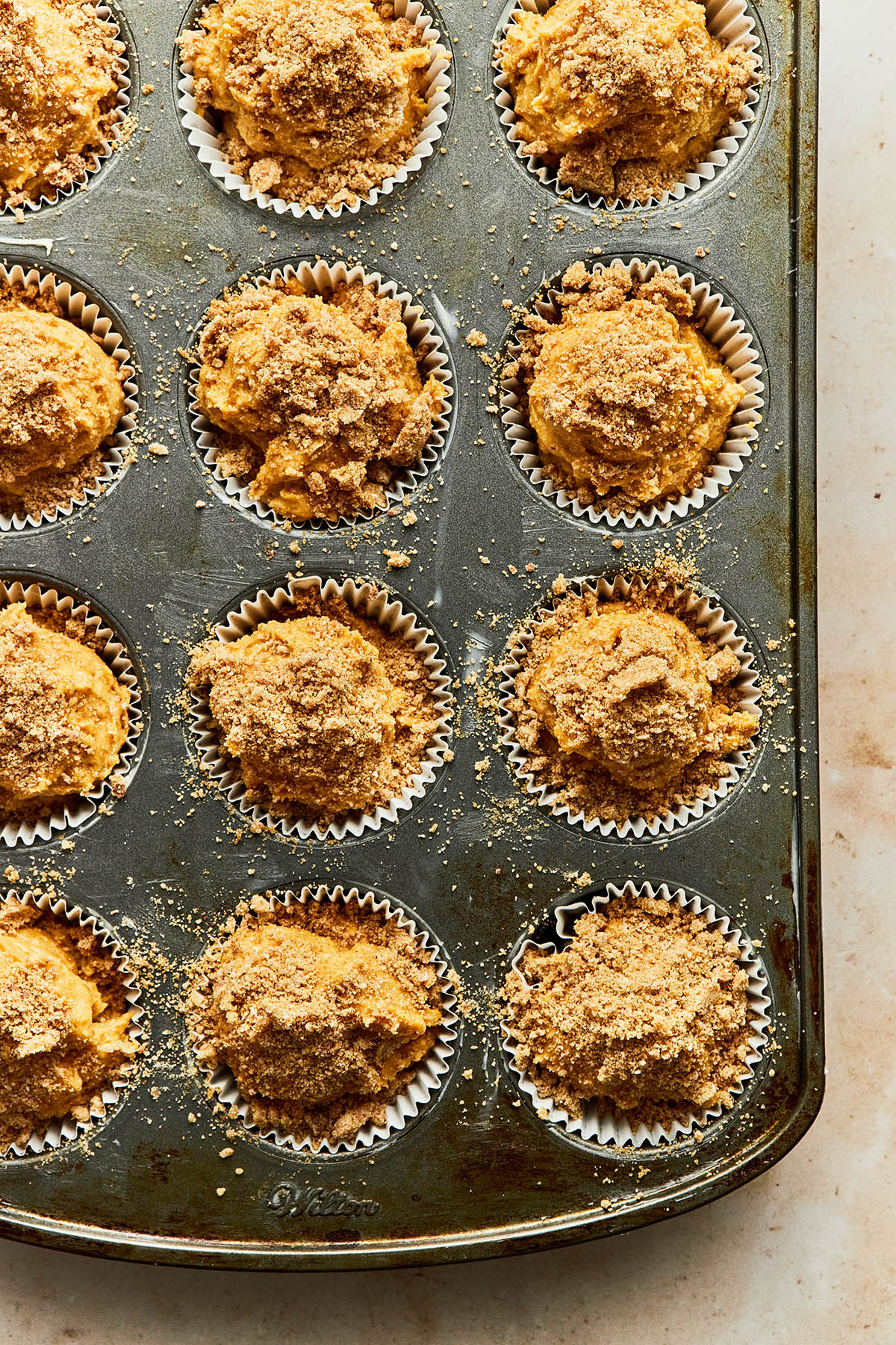 unbaked muffin batter, topped with streusel, in a muffin tin.