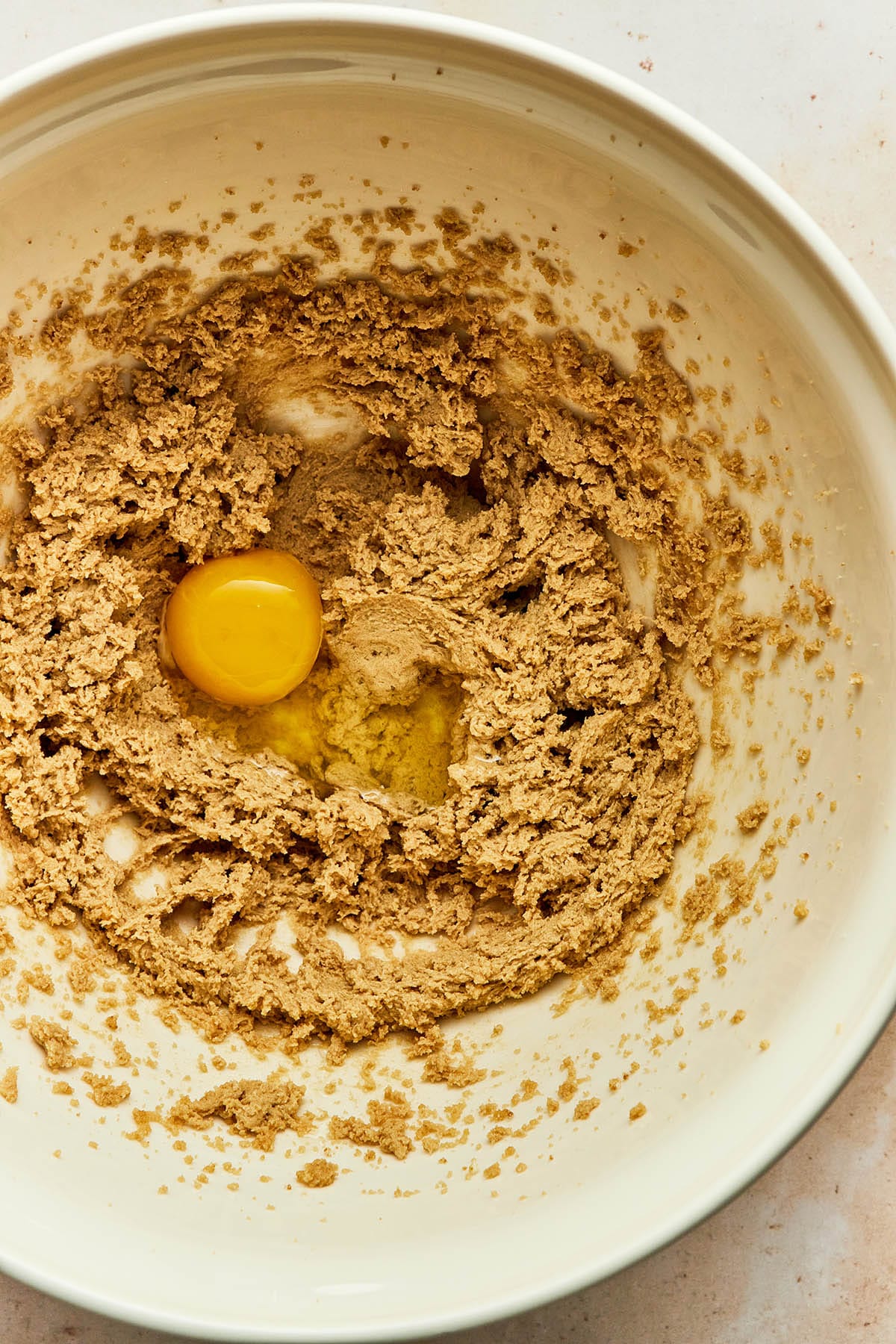 Overhead image of an unmixed eeg in a bowl of creamed butter and sugar.